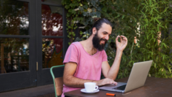 Man smoking joint and working on his laptop with a coffee cup in front of him