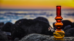 bong on right side of image sitting on rock at sunset