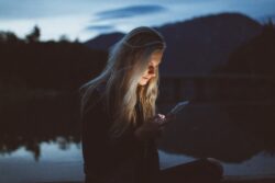 girl reading off her phone by a lake